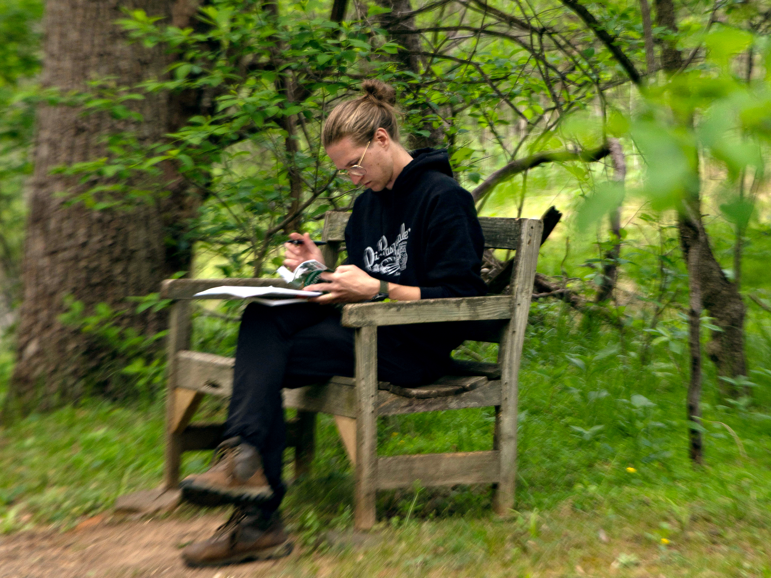 Sketching in a journal on a bench in the forest