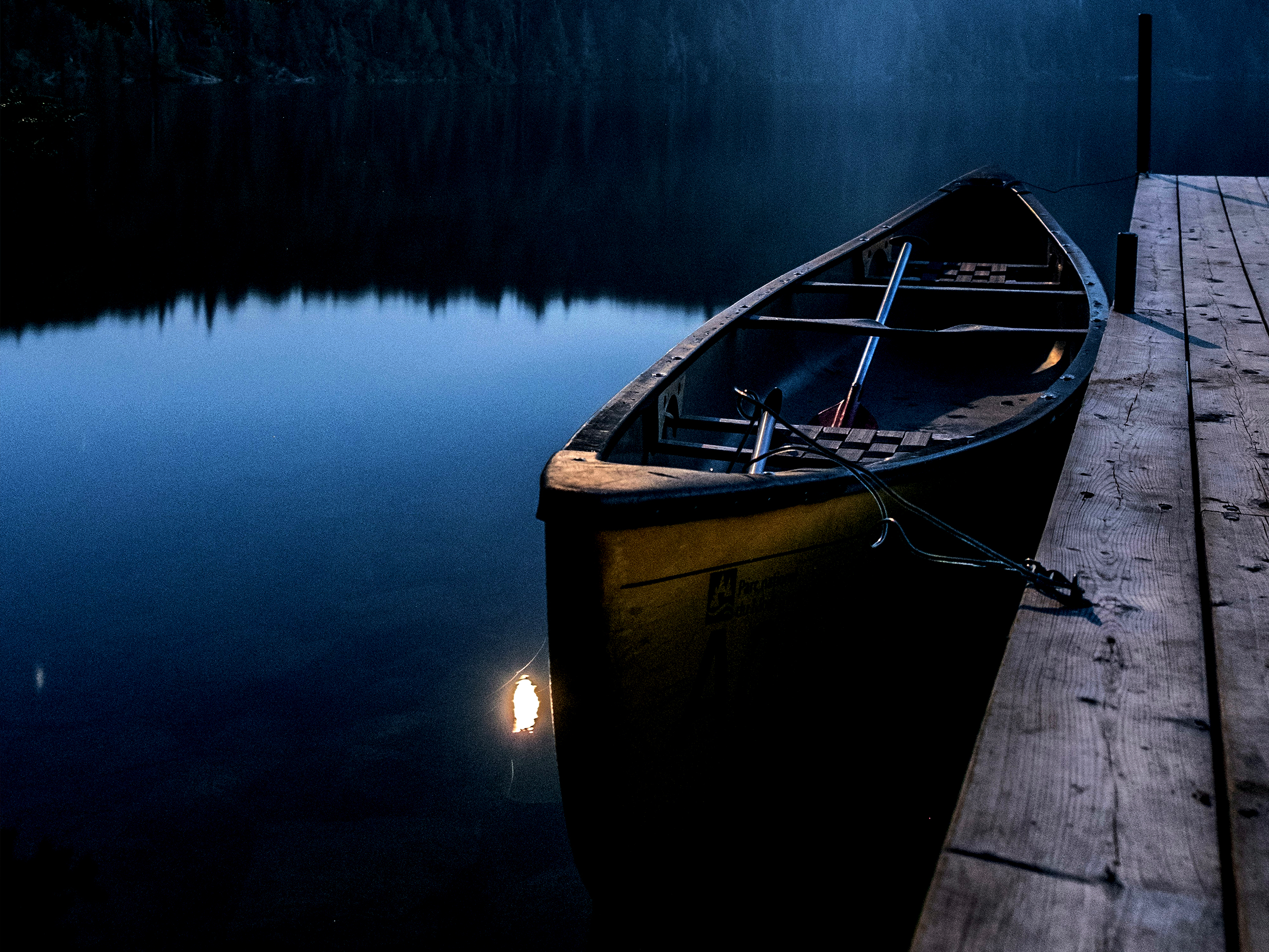 A canoe at the dock on a still lake at night