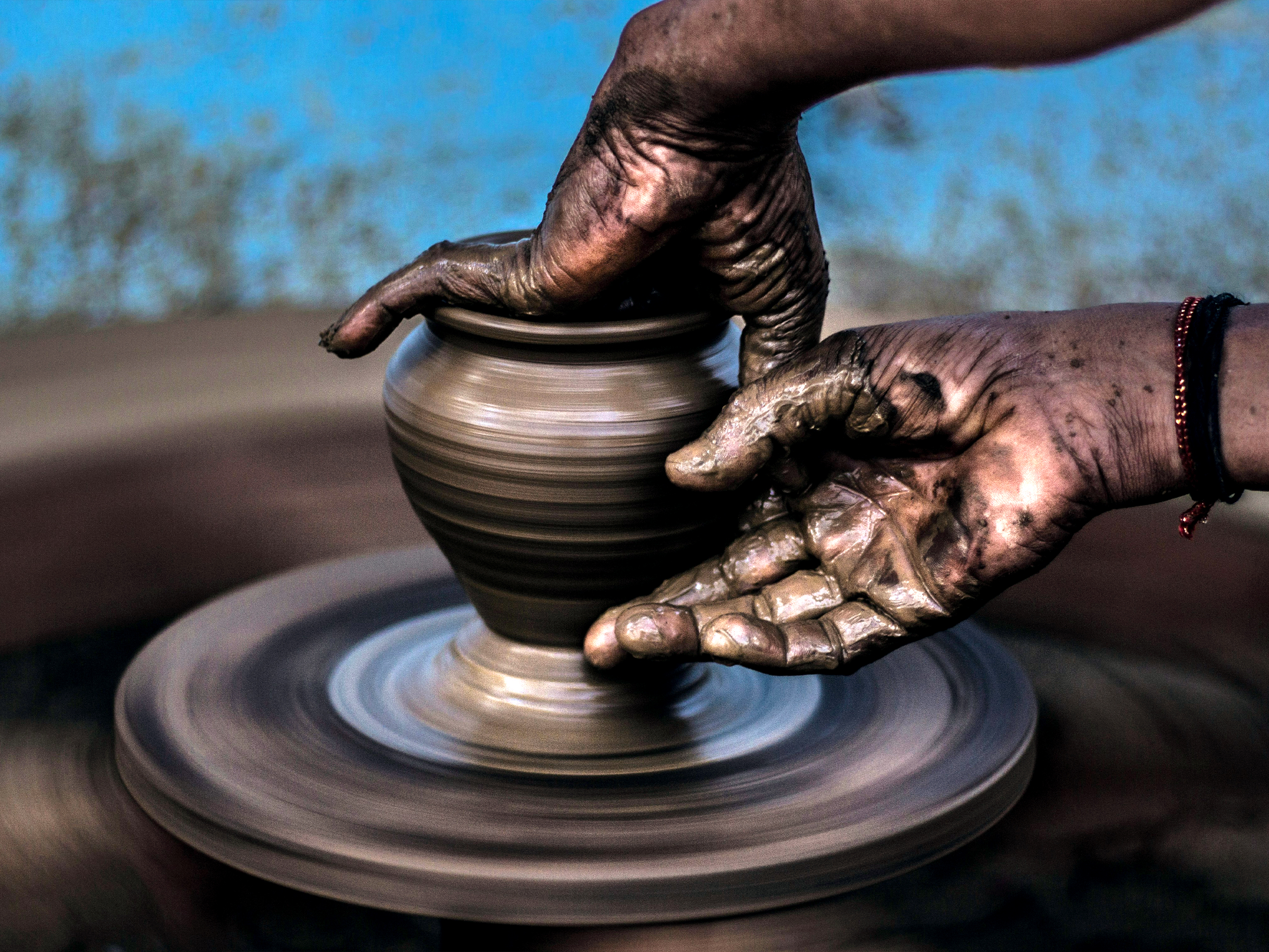 Hands shaping clay on a pottery wheel